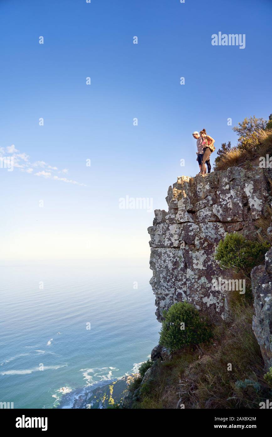 Couple on cliff over sunny ocean Cape Town South Africa Stock Photo