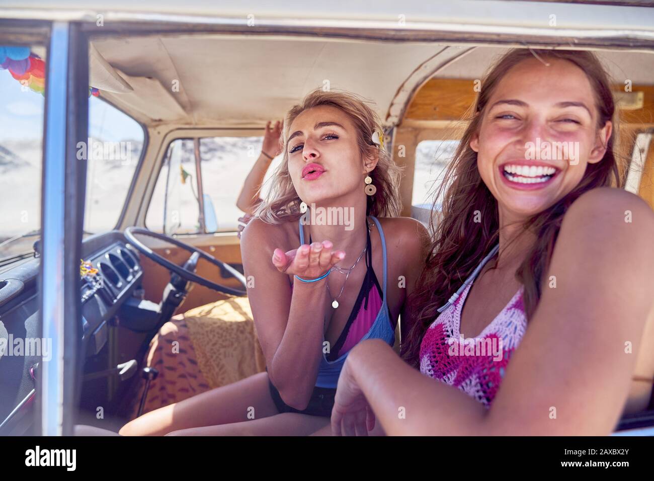 Portrait playful young women friends blowing a kiss inside van Stock Photo