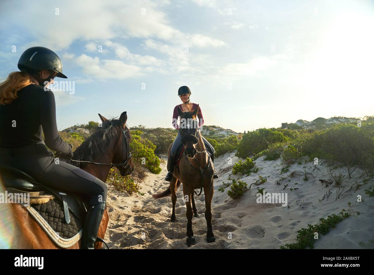 Young women horseback riding on sunny beach Stock Photo