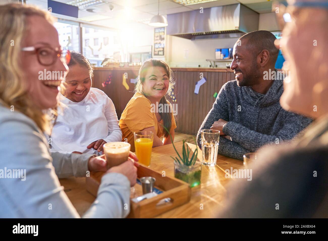 Young women with Down Syndrome laughing with friends in cafe Stock Photo
