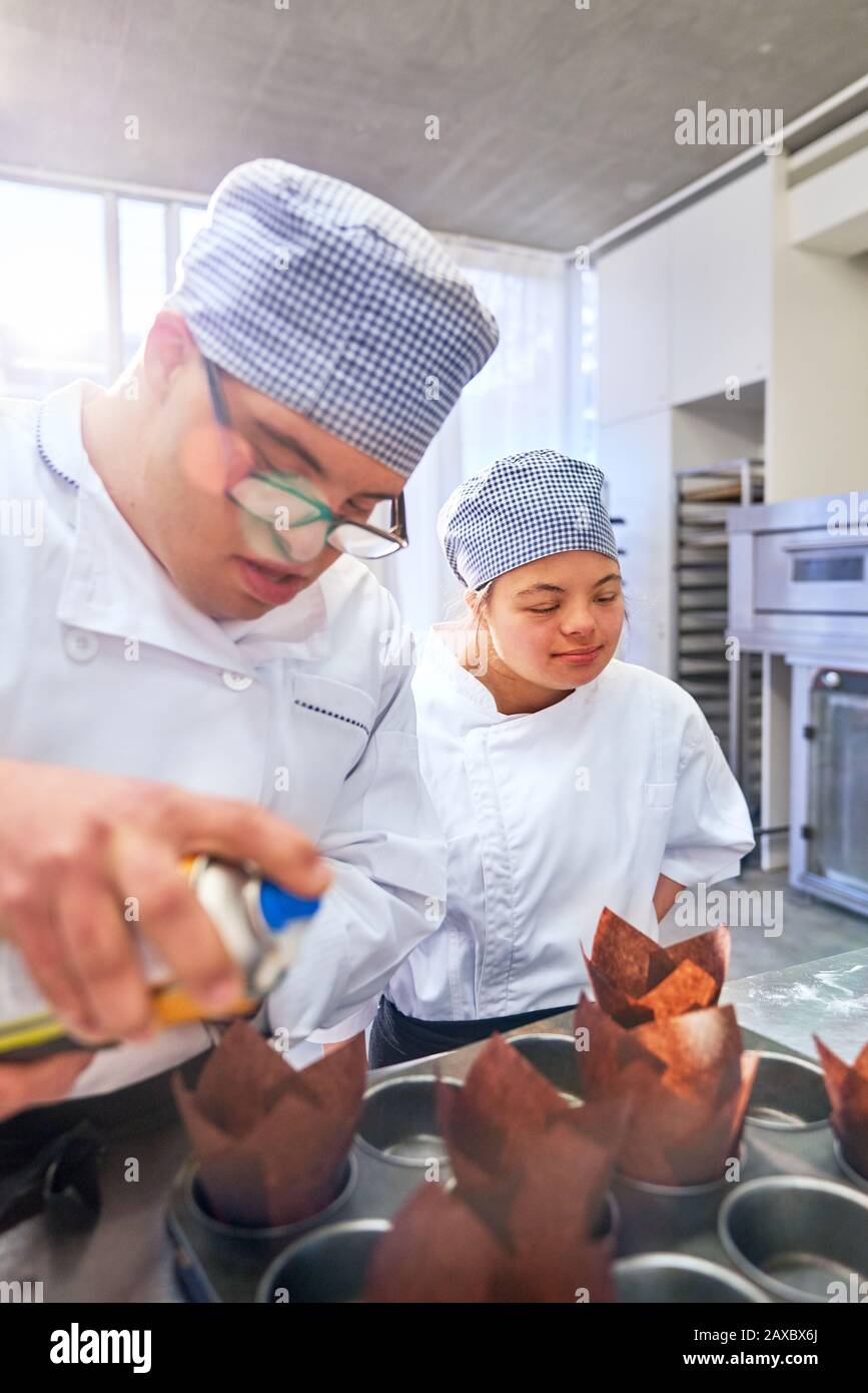 Students with Down Syndrome baking muffins in kitchen Stock Photo