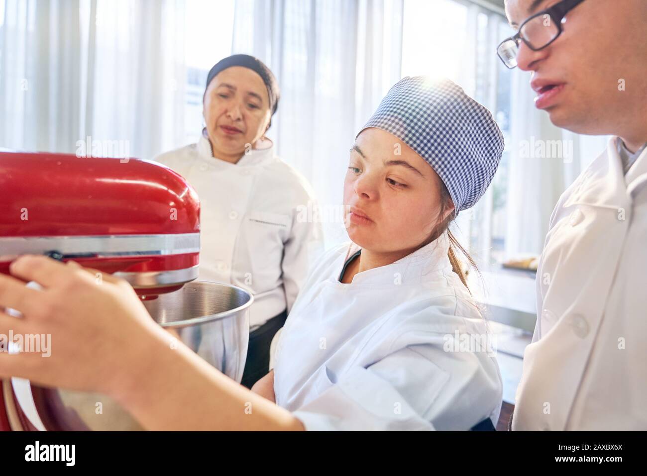 Students with Down Syndrome using stand mixer in baking class Stock Photo