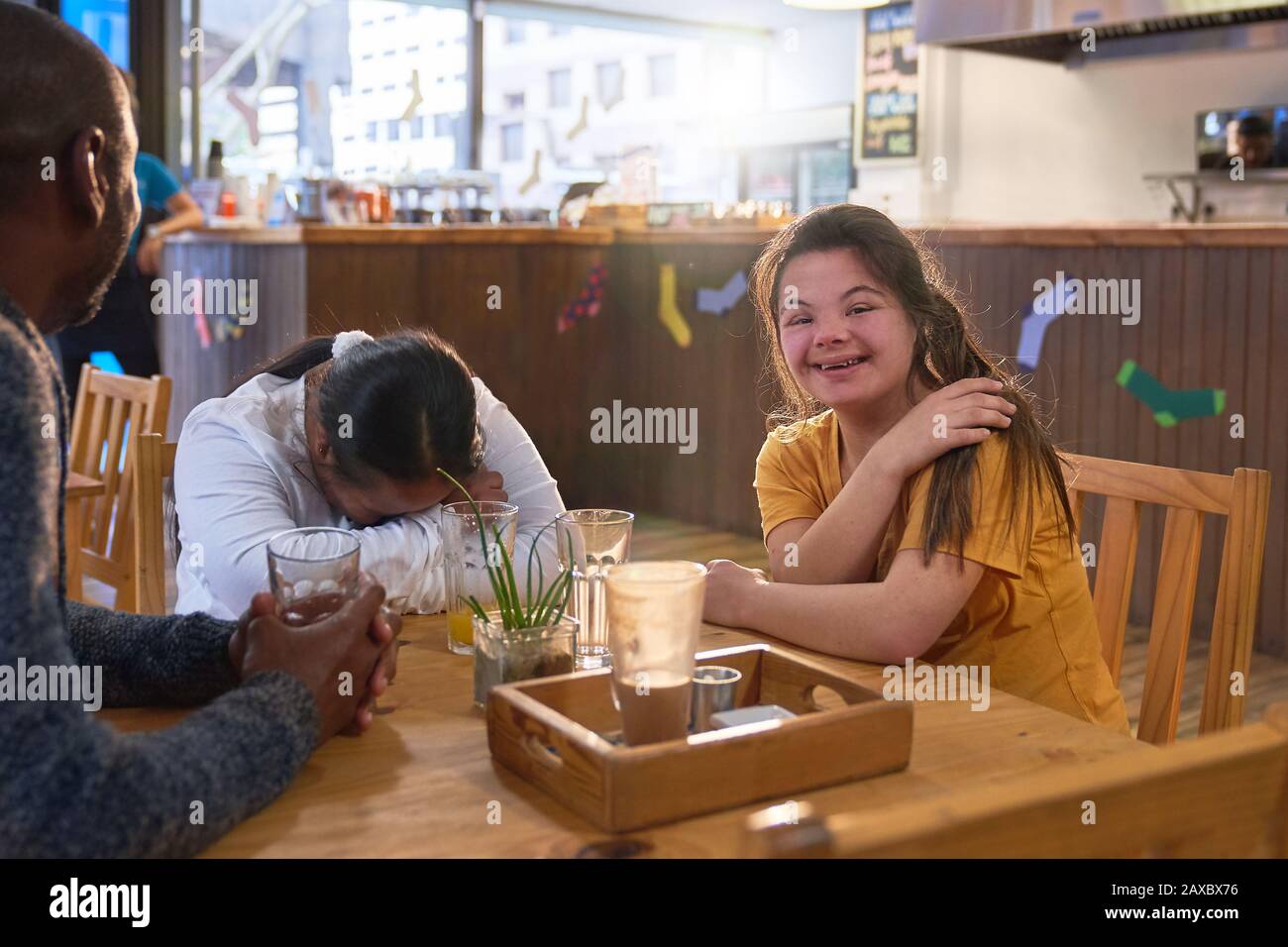 Happy young woman with Down Syndrome laughing with friends in cafe Stock Photo