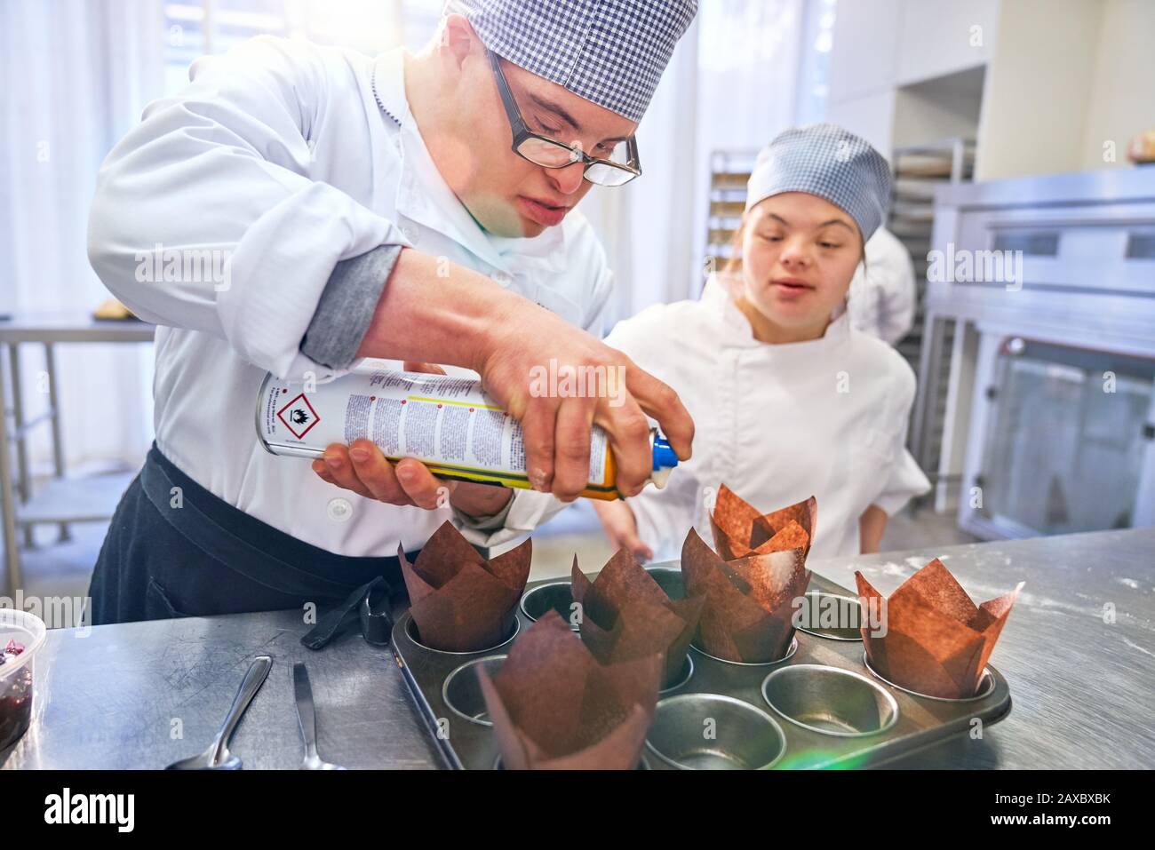 Students with Down Syndrome baking muffins in kitchen Stock Photo
