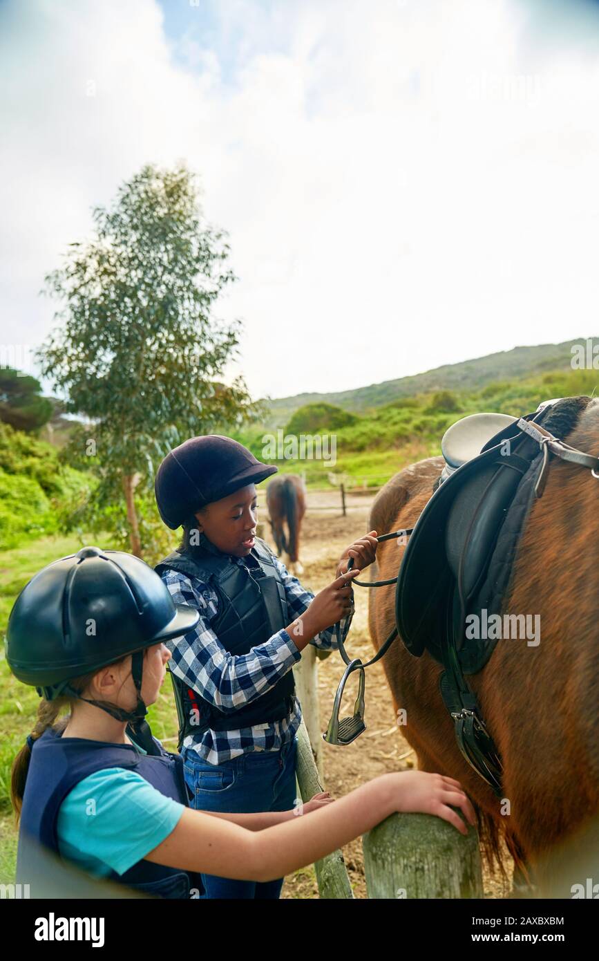 Girls adjusting stirrups for horseback riding Stock Photo