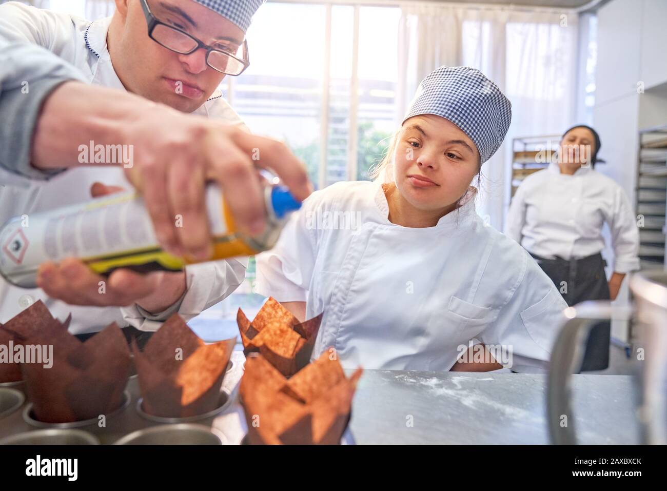 Young students with Down Syndrome baking muffins in kitchen Stock Photo