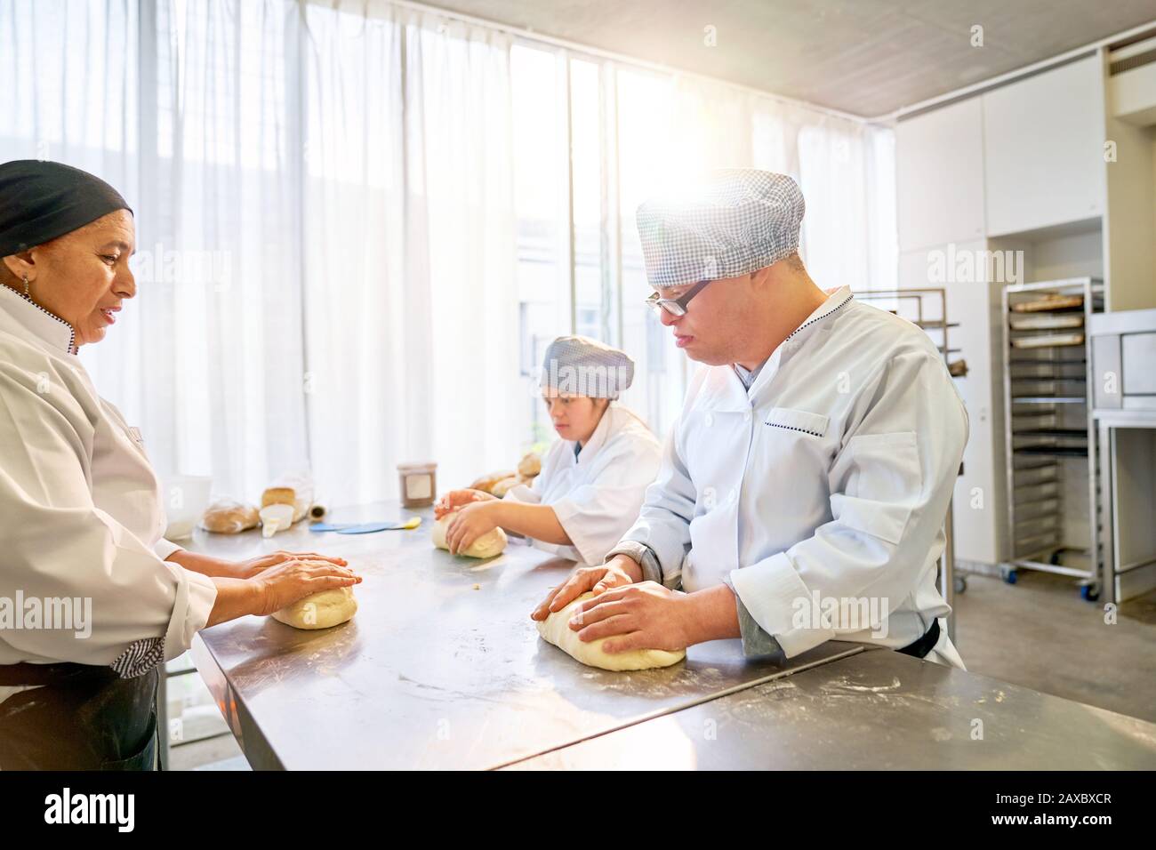 Chef teaching students with Down Syndrome how to bake in kitchen Stock Photo