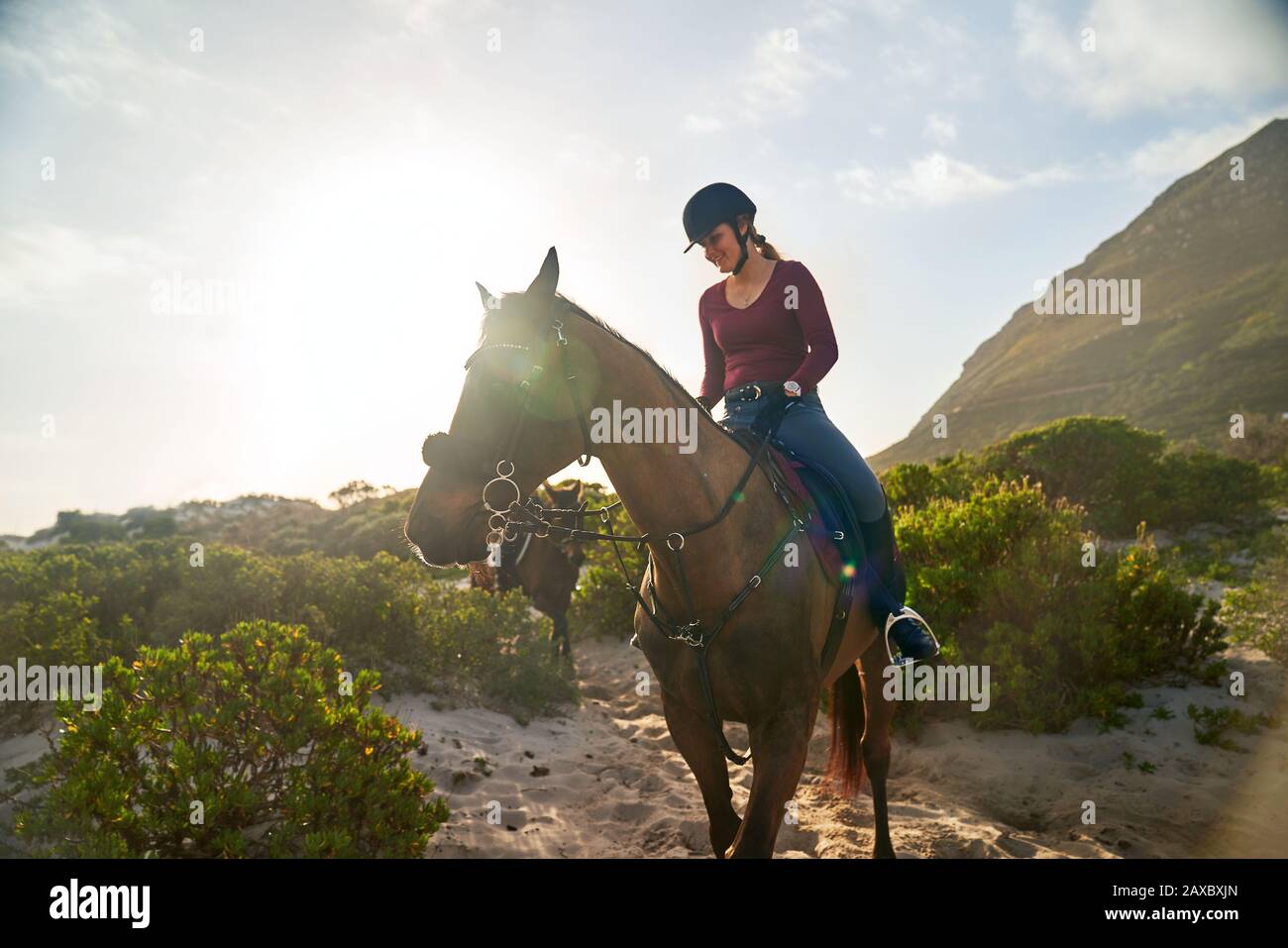 Young woman horseback riding on sunny beach Stock Photo