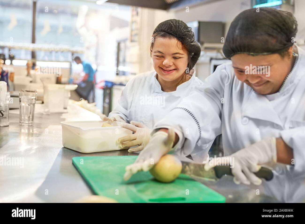Happy young women with Down Syndrome cooking in restaurant Stock Photo