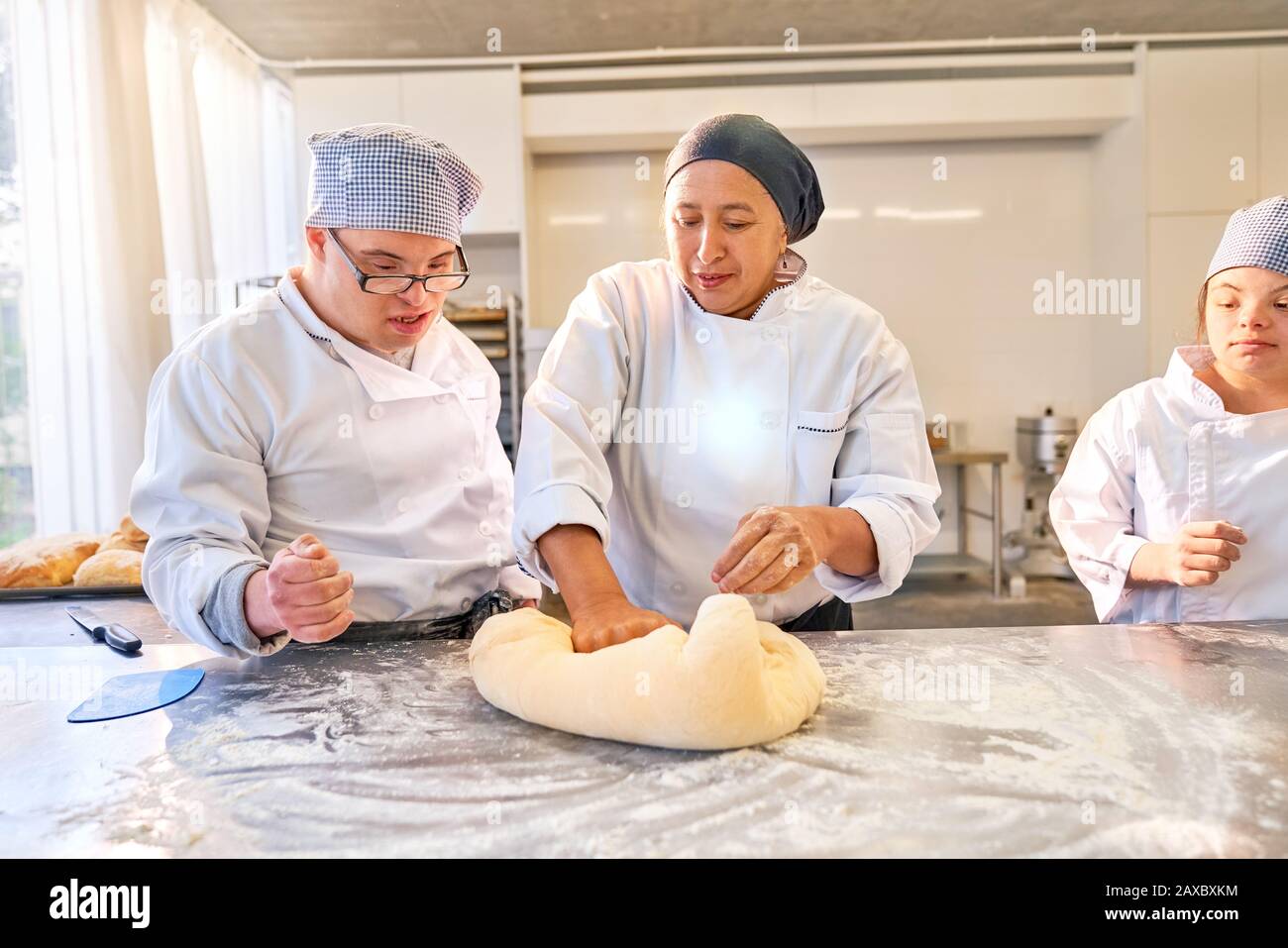 Instructor teaching students with Down Syndrome how to roll dough Stock Photo