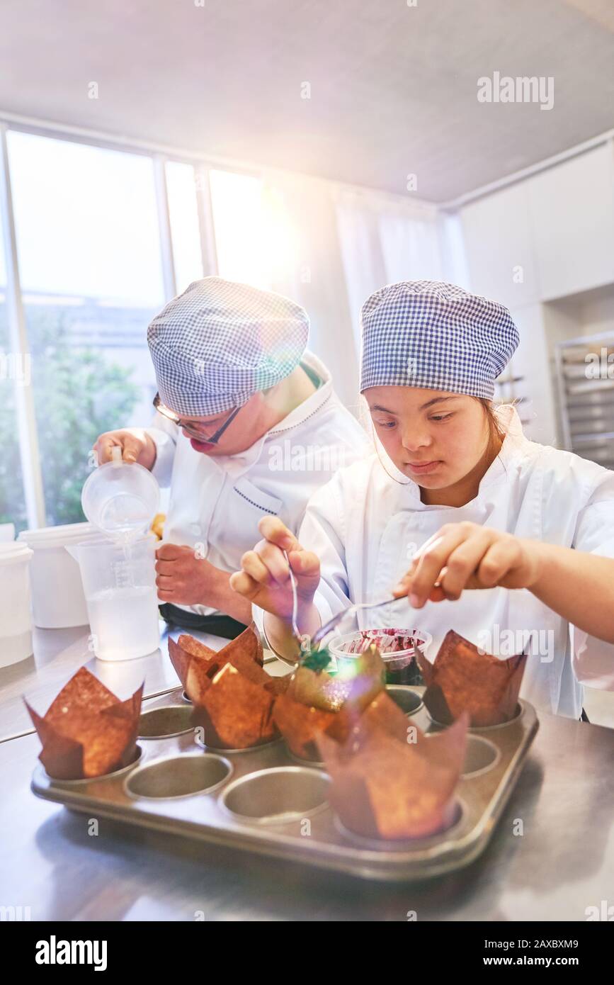Young students with Down Syndrome baking muffins in kitchen Stock Photo