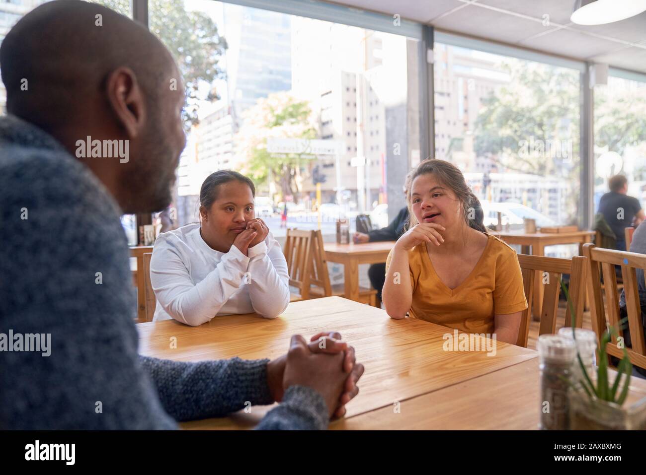 Mentor and young women with Down Syndrome talking in cafe Stock Photo