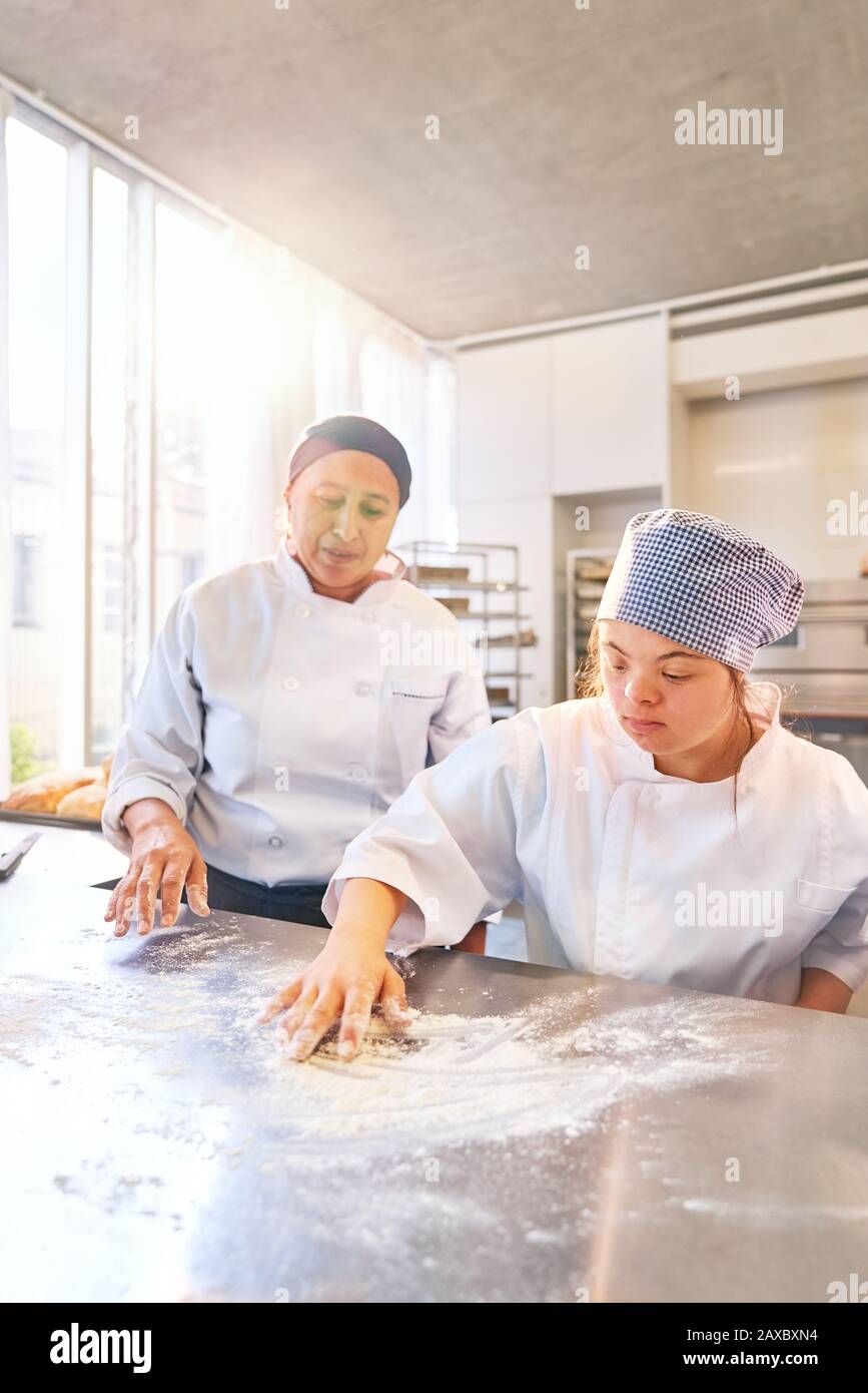 Baking instructor and young student with Down Syndrome flour surface ...