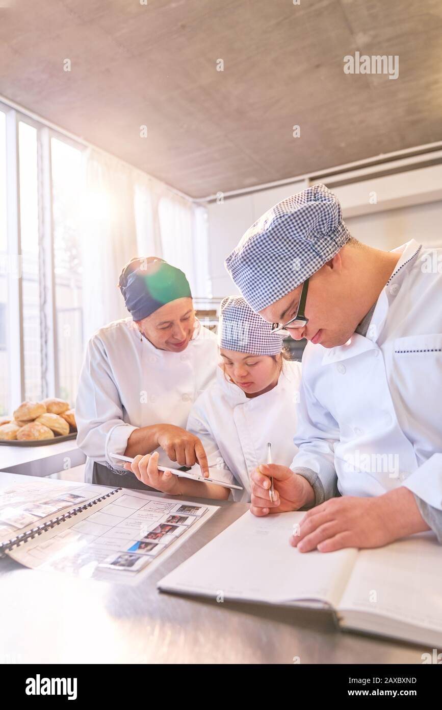 Chef and students with Down Syndrome using digital tablet in kitchen Stock Photo