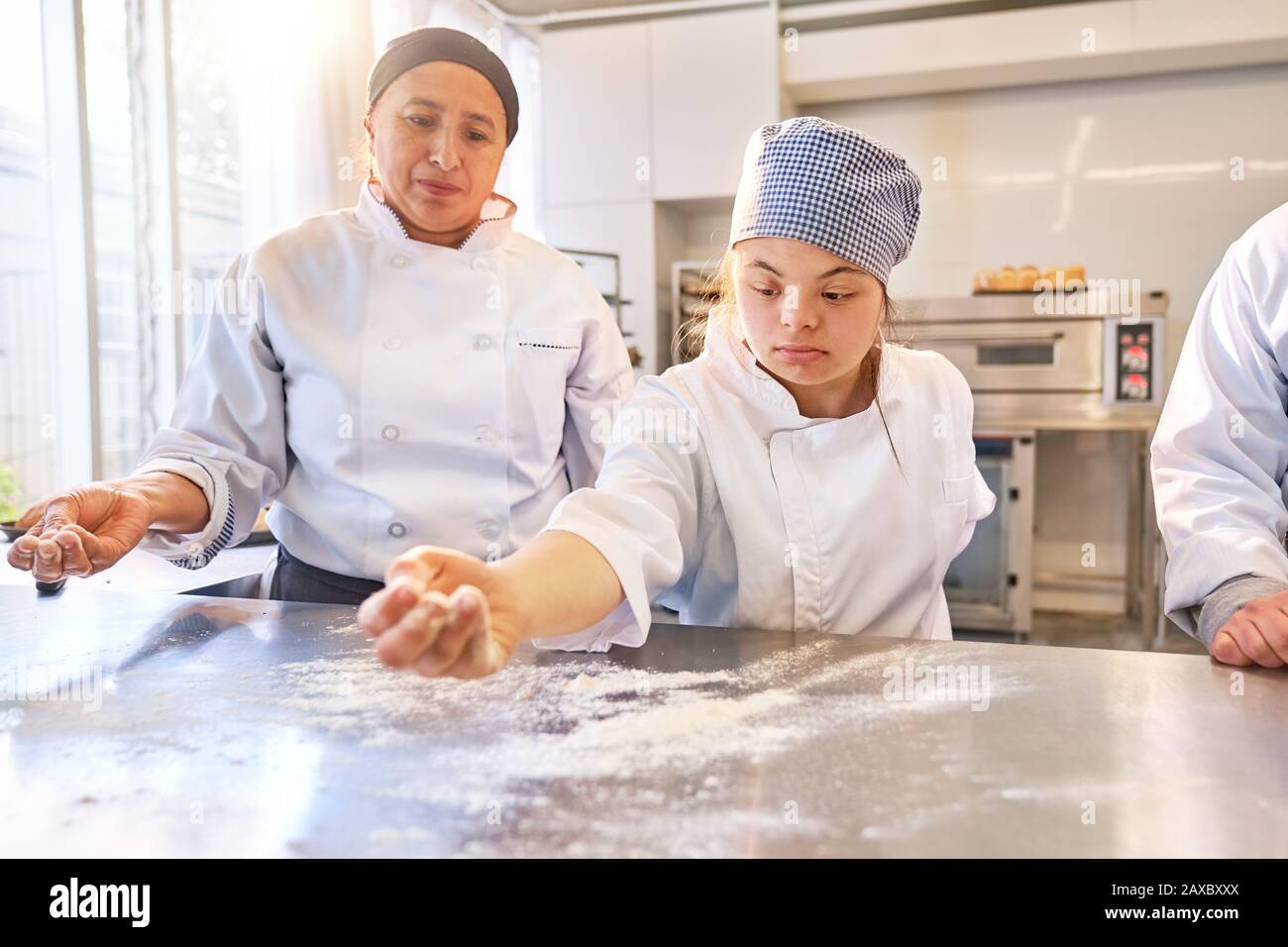 Young woman with Down Syndrome flouring surface in baking class Stock Photo