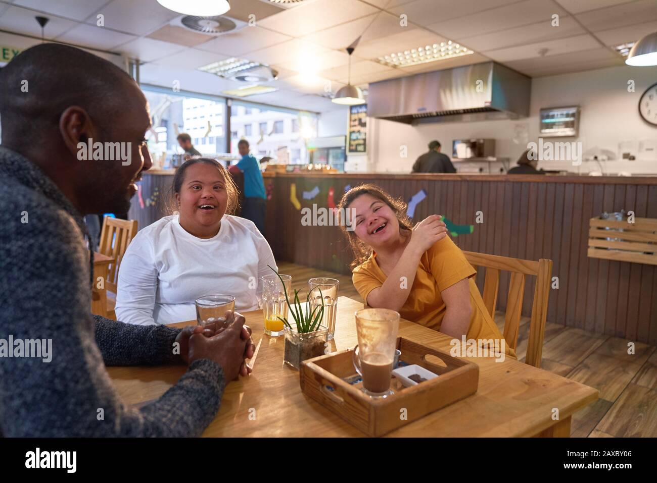 Happy young women friends with Down Syndrome laughing in cafe Stock Photo