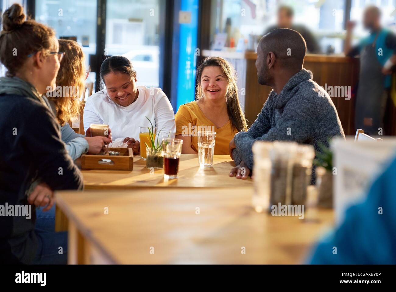 Young women with Down Syndrome talking with friends in cafe Stock Photo