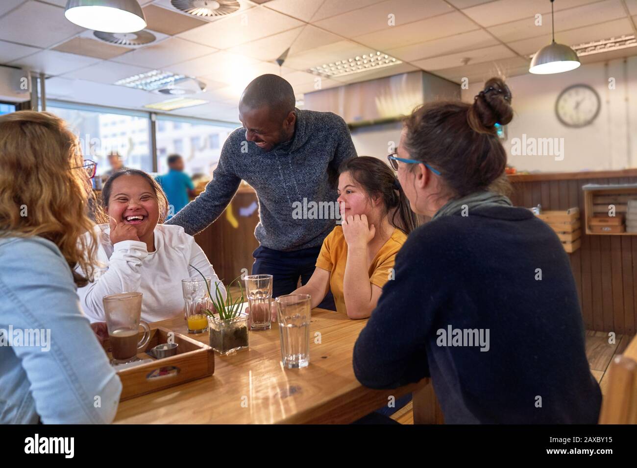 Happy young women with Down Syndrome in cafe with friends Stock Photo