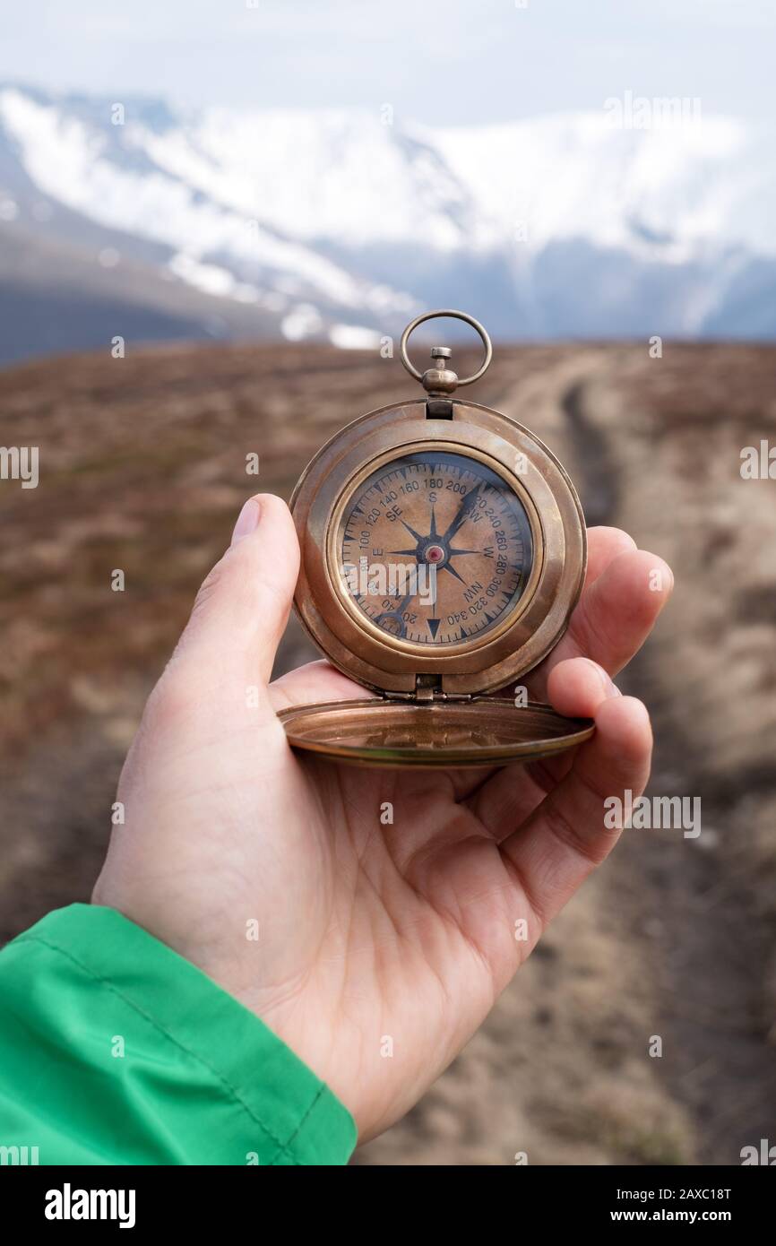 Man with retro compass in hand in high mountains. Travel concept. Landscape photography Stock Photo