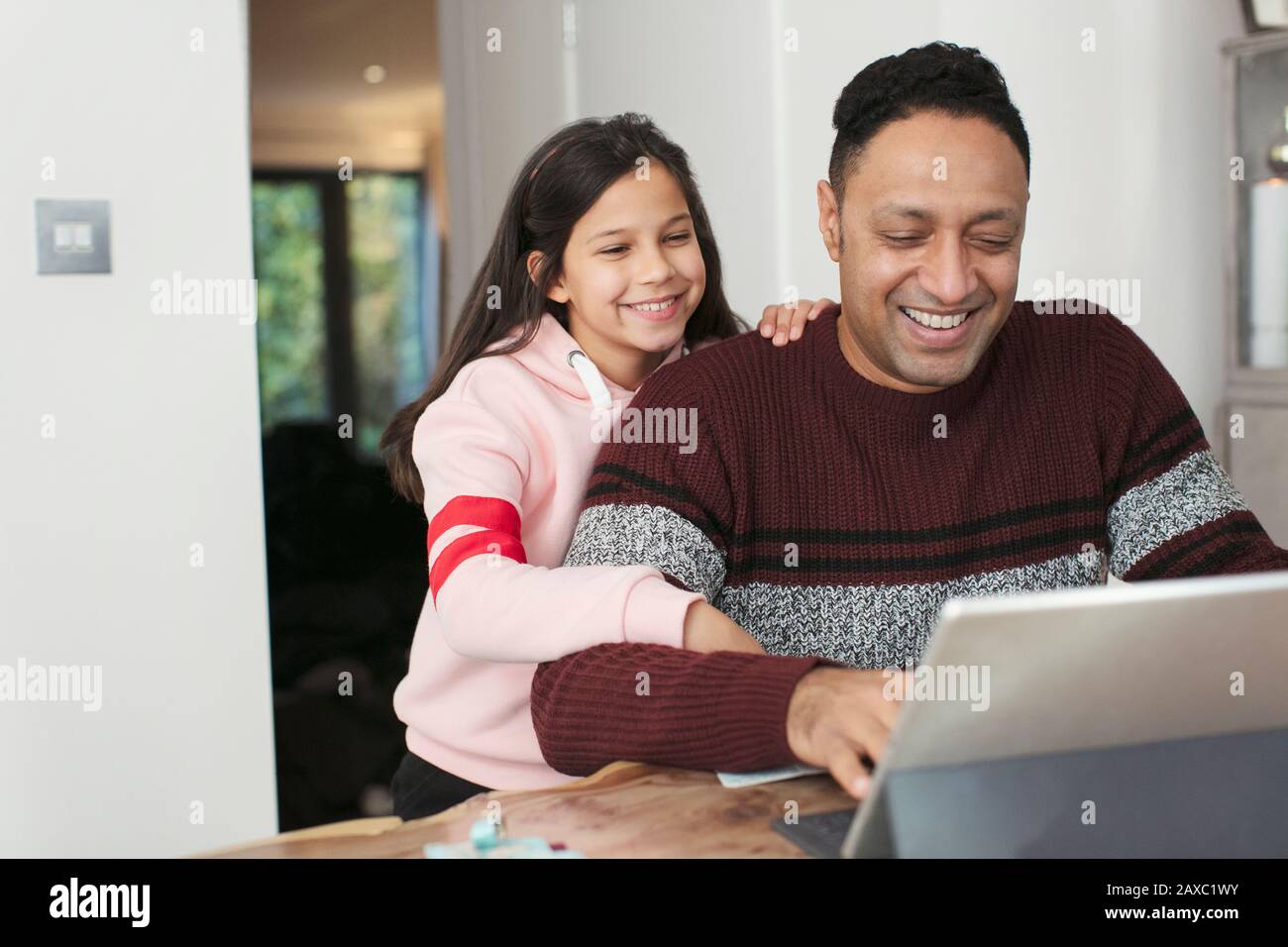 Smiling father and daughter using digital tablet at table Stock Photo