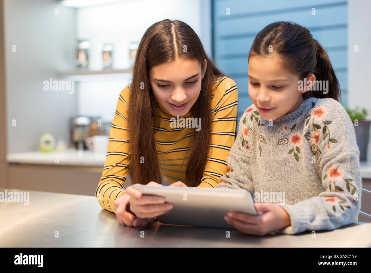 Sisters using digital tablet in kitchen Stock Photo