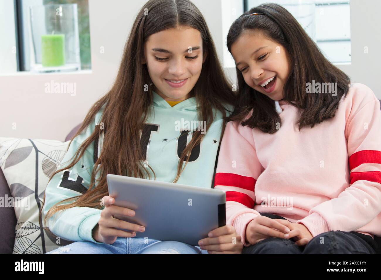 Smiling sisters using digital tablet Stock Photo