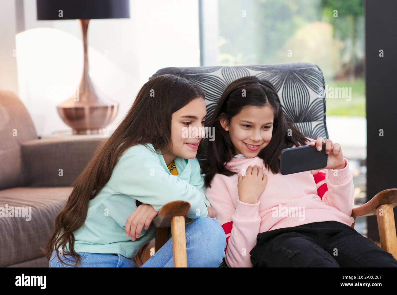 Sisters using smart phone in living room Stock Photo
