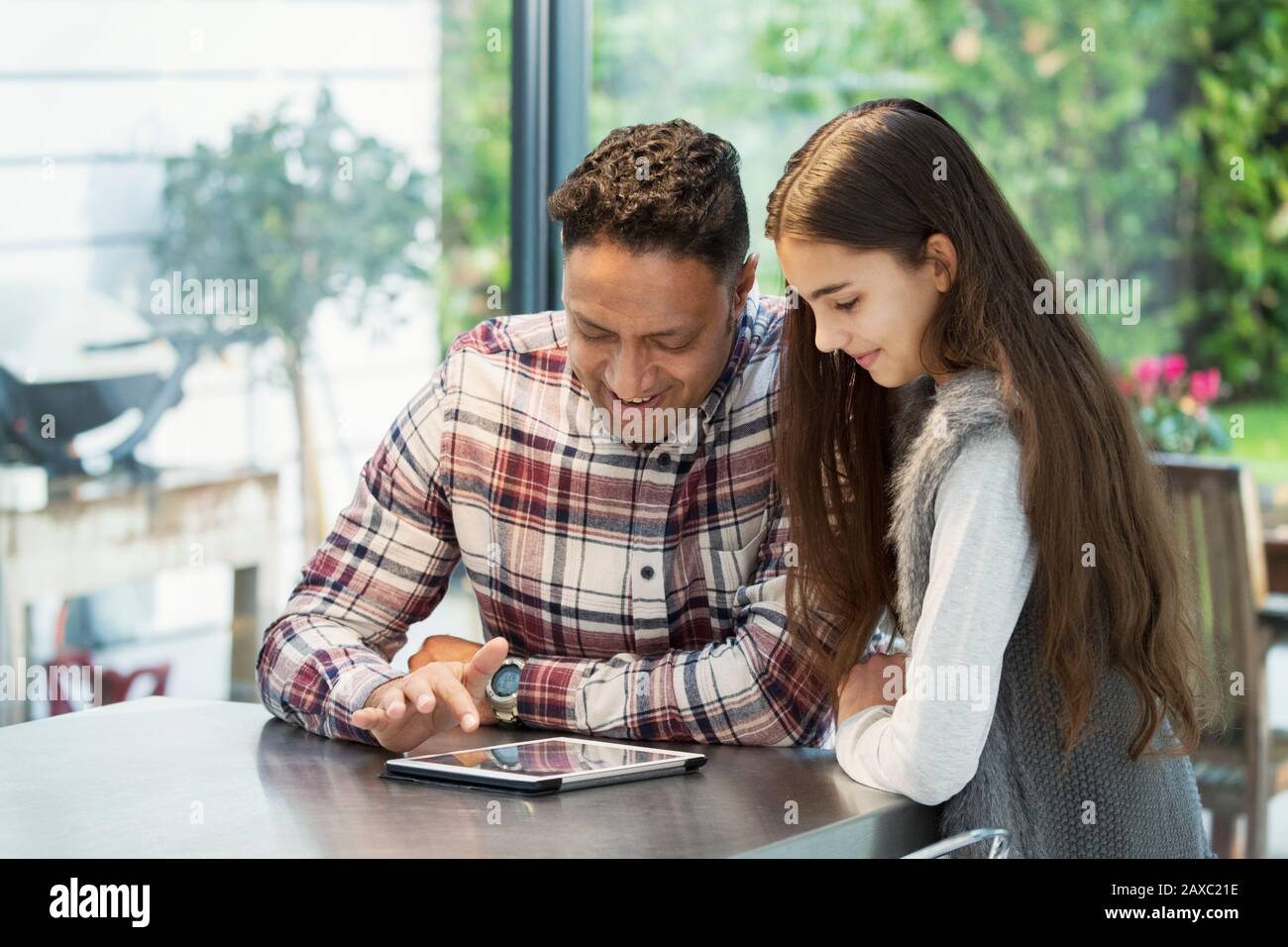 Father and daughter using digital tablet in kitchen Stock Photo