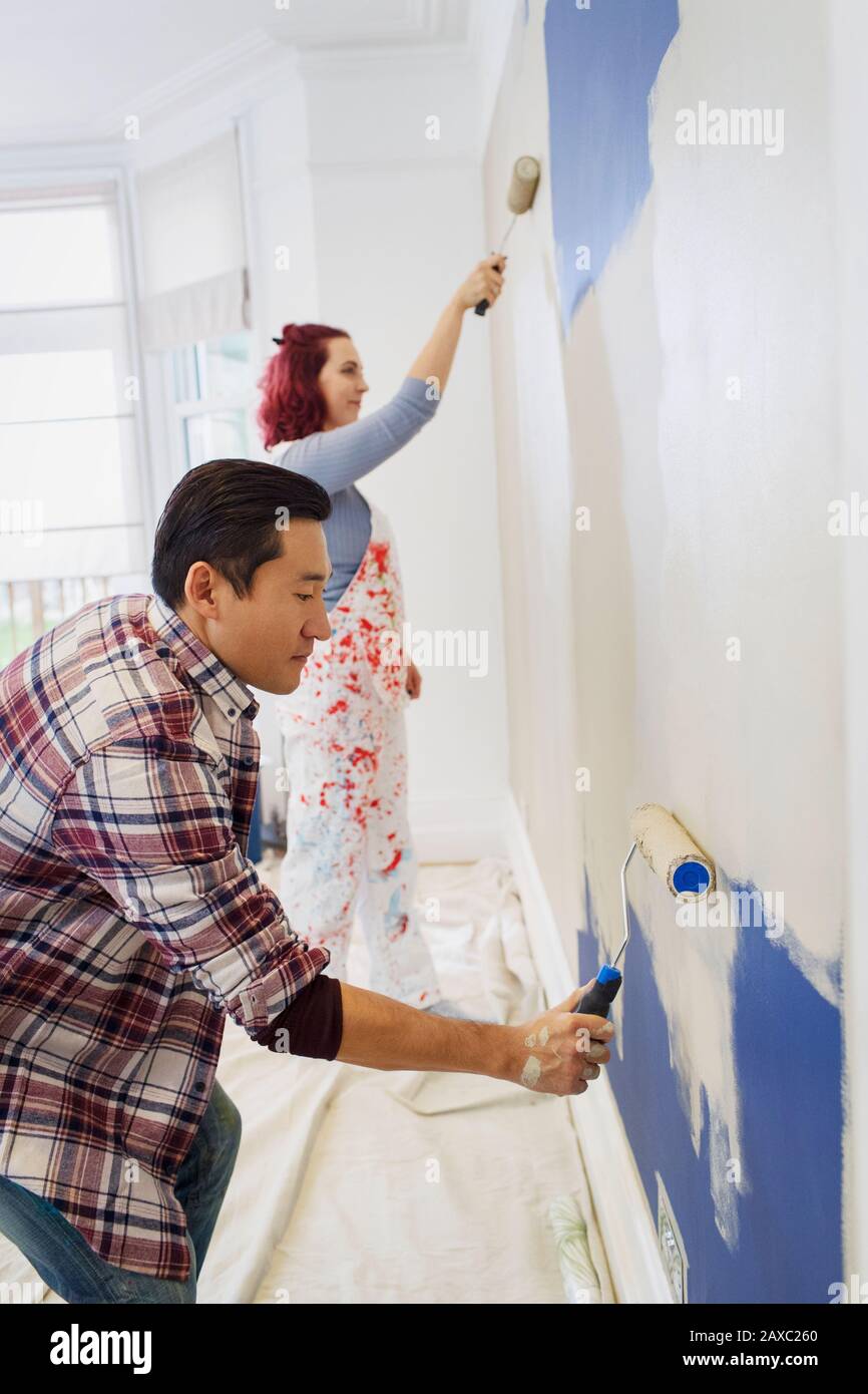 Couple painting wall with paint rollers Stock Photo