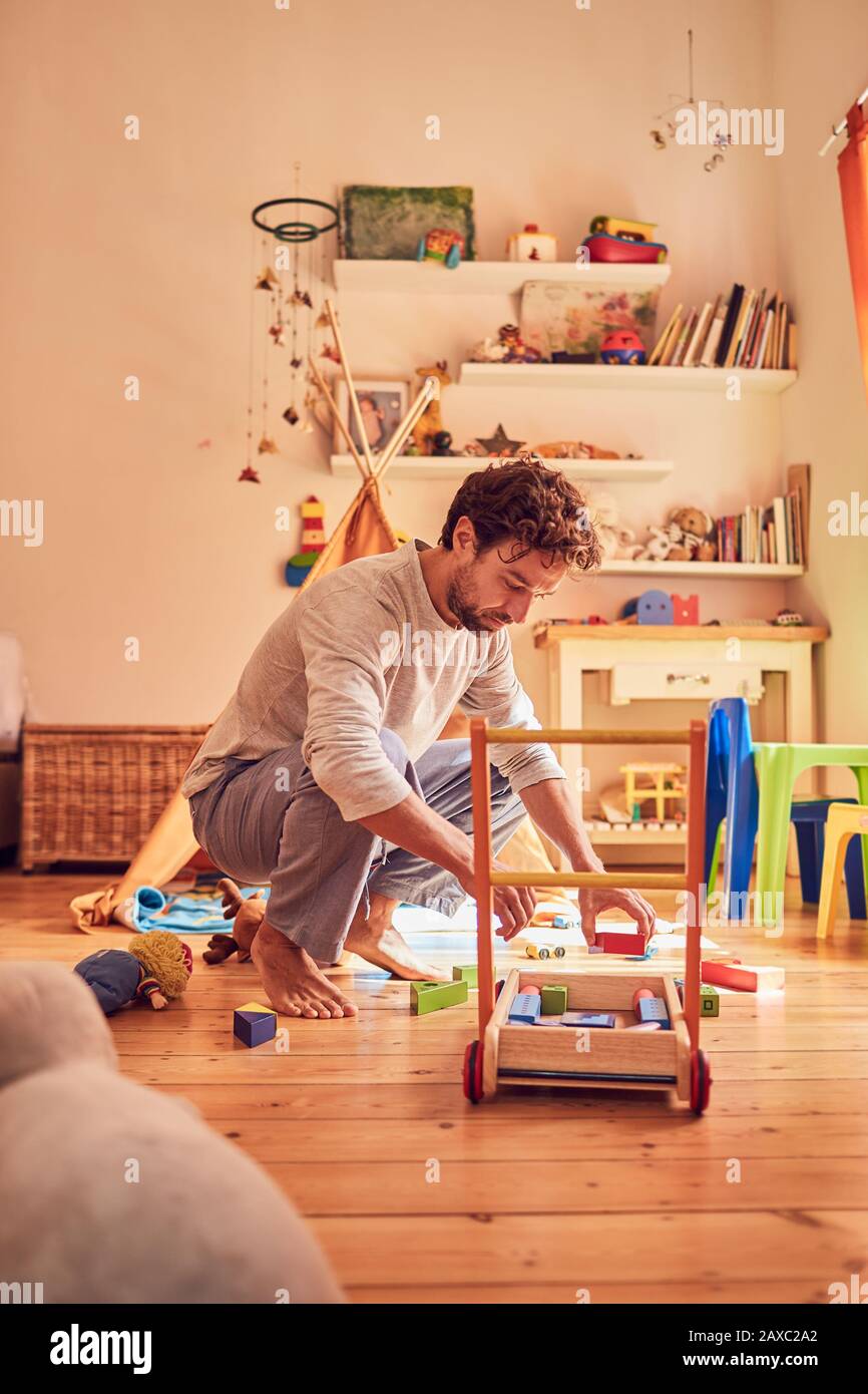Father picking up toys in child’s bedroom Stock Photo