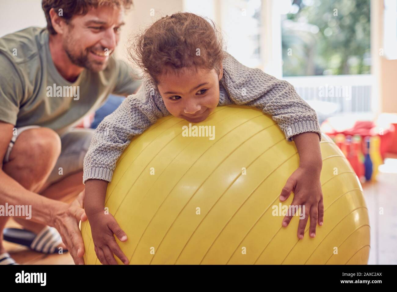 Father and daughter playing on fitness ball Stock Photo