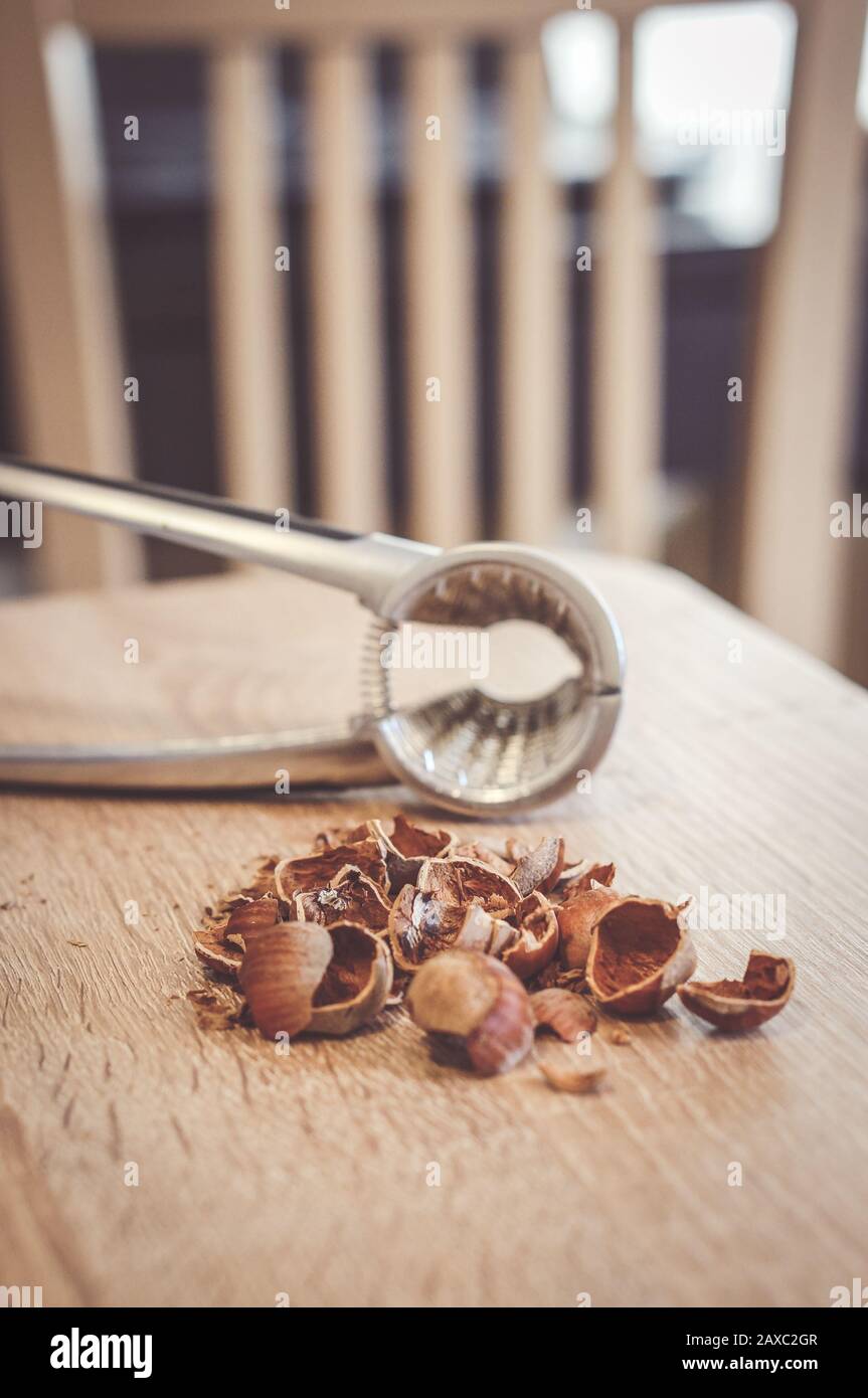 Soft focus shot of broken hazelnut nut shells on a table with a nutcracker Stock Photo