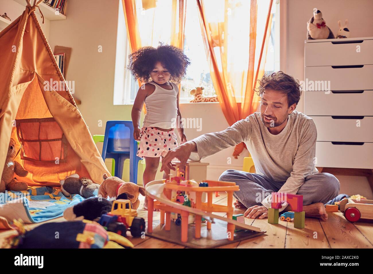 Father and daughter playing with toys on floor Stock Photo