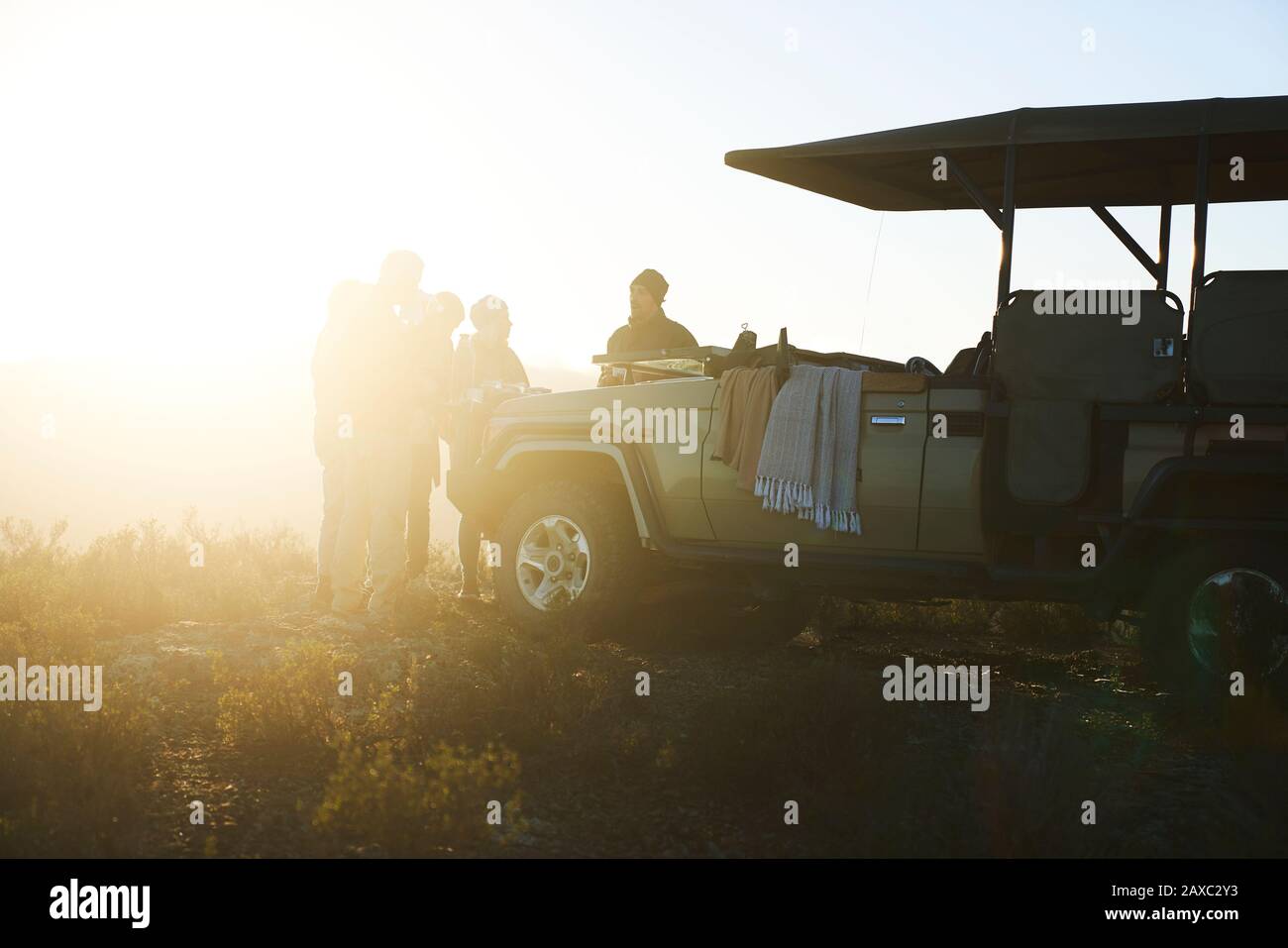 Safari tour group drinking tea outside sunny off-road vehicle Stock Photo