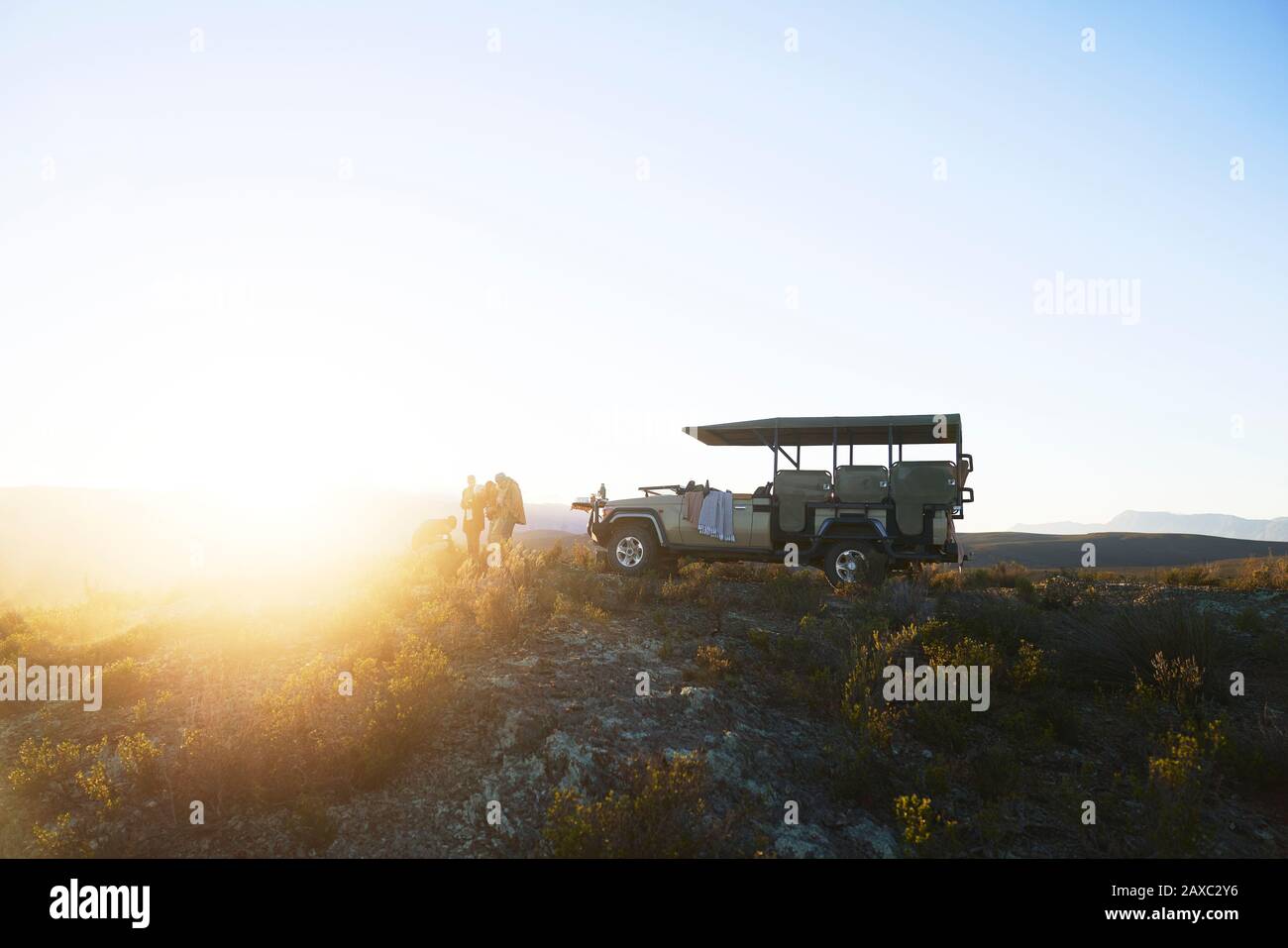 Safari tour group outside off-road vehicle on tranquil hill at sunrise Stock Photo