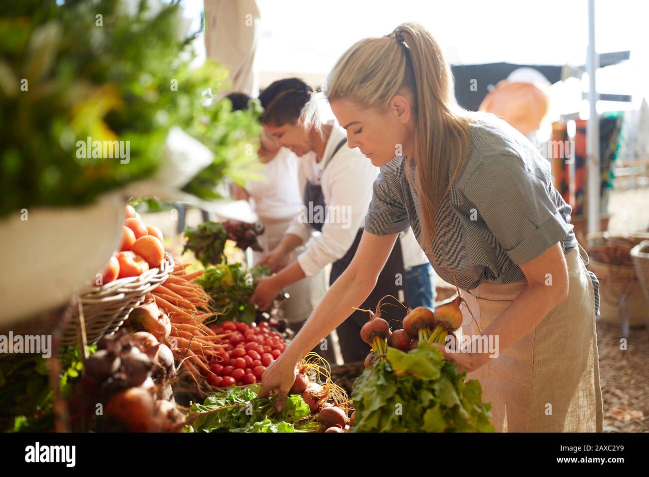 Woman working, arranging produce at farmer’s market Stock Photo