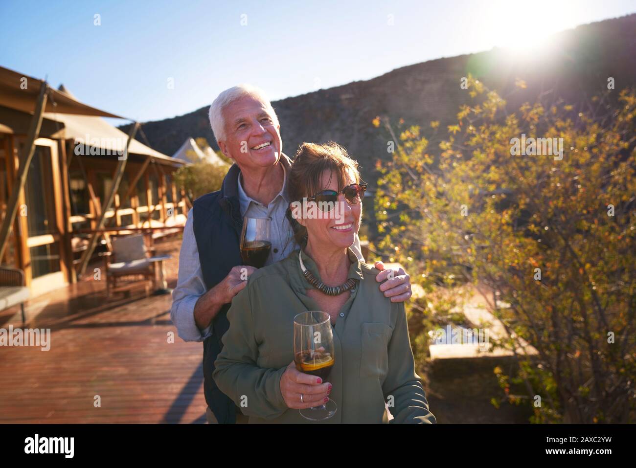 Happy senior couple drinking iced tea on sunny safari lodge balcony Stock Photo