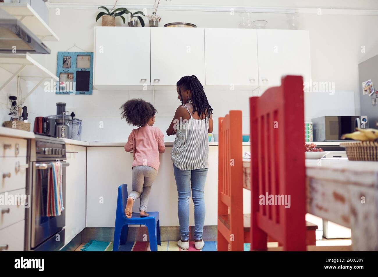 Mother and daughter doing dishes at kitchen sink Stock Photo