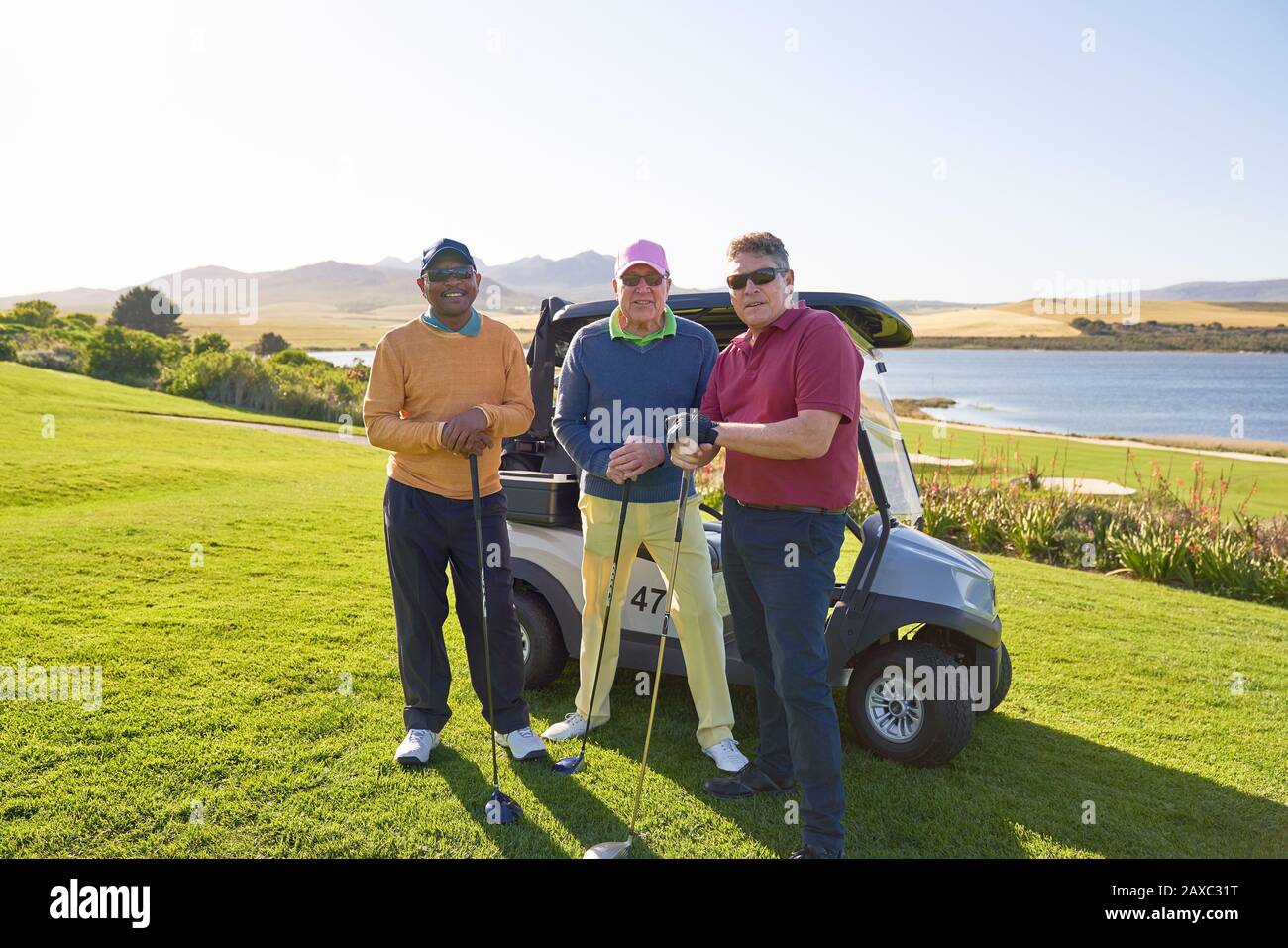 Portrait confident mature male friends golfing on sunny golf course Stock Photo
