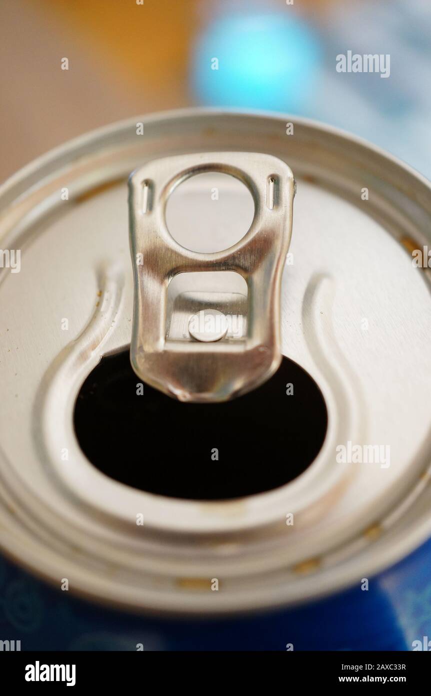Closeup shot of a the top of an opened soda can with the tab lifted