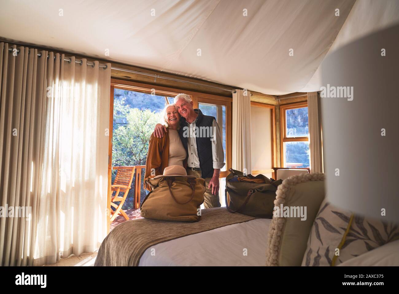 Portrait happy senior couple hugging in hotel bedroom Stock Photo