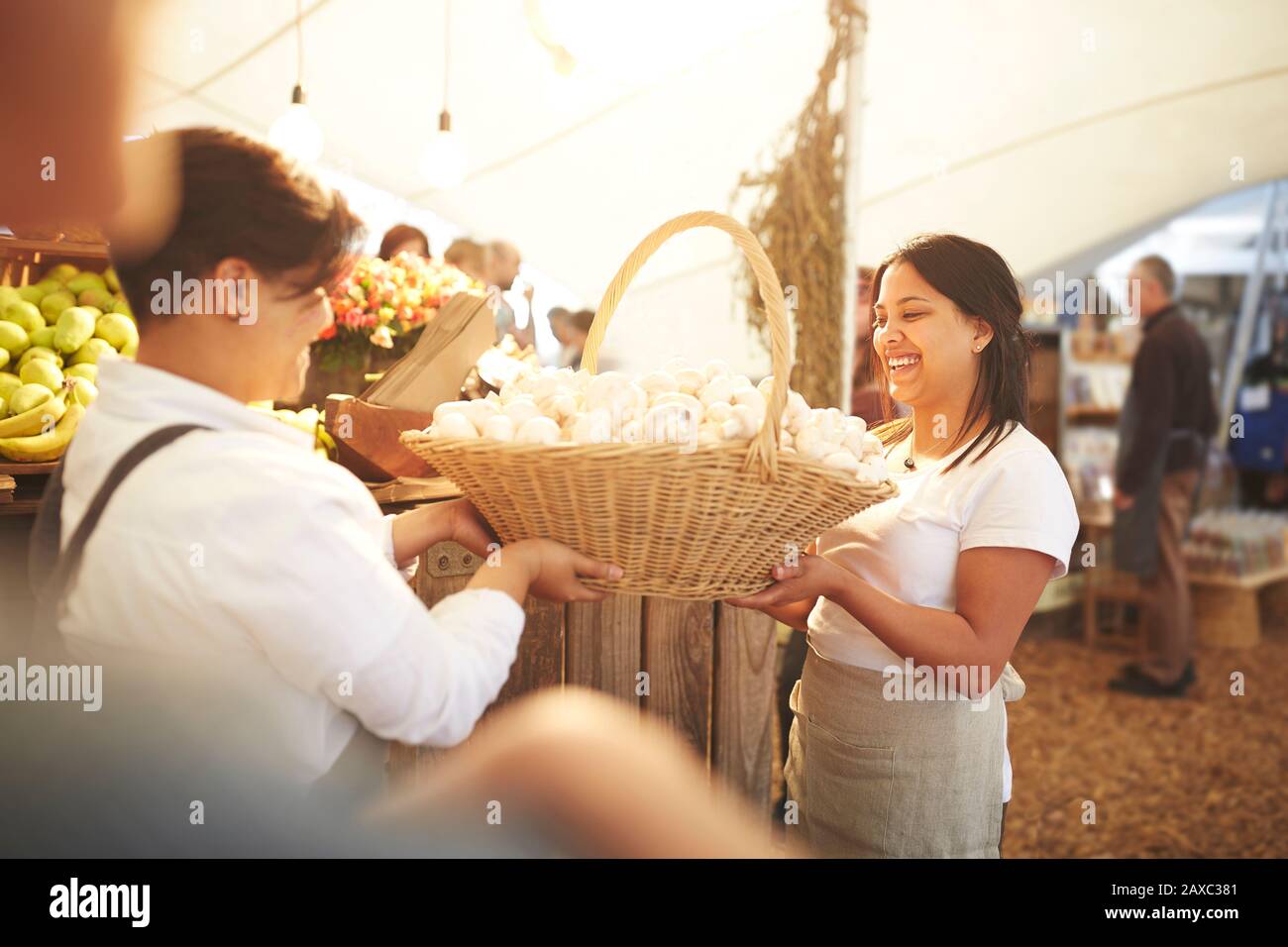Women workers carrying basket of fresh garlic at farmer’s market Stock Photo