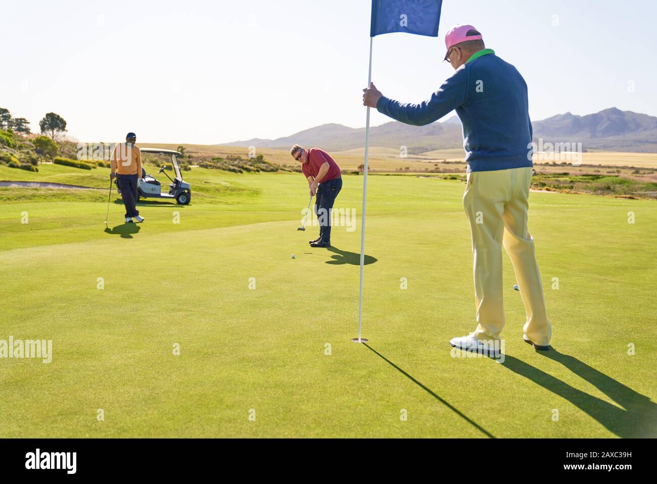 Men on sunny golf putting green Stock Photo
