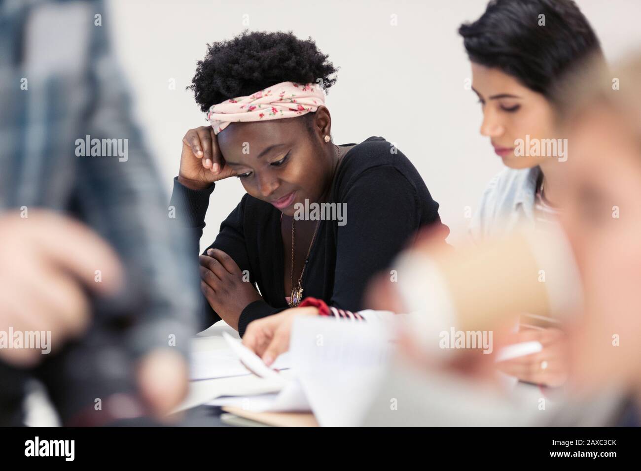 Female community college students reviewing paperwork in classroom Stock Photo