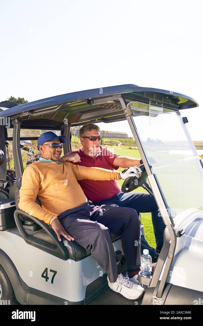 Mature male golfers riding in golf cart Stock Photo