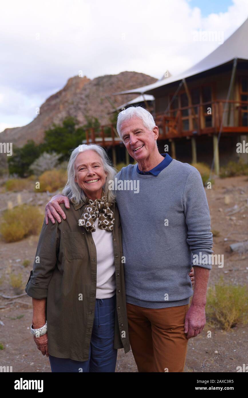 Portrait happy senior couple outside safari lodge cabin Stock Photo