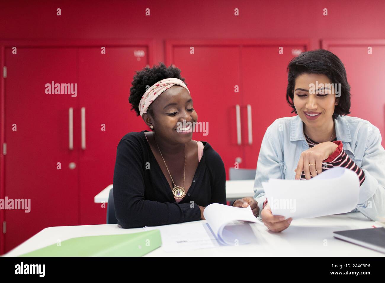 Female community college students discussing paperwork in classroom Stock Photo