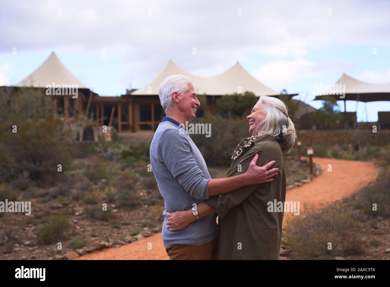 Affectionate senior couple hugging outside safari lodge hotel Stock Photo