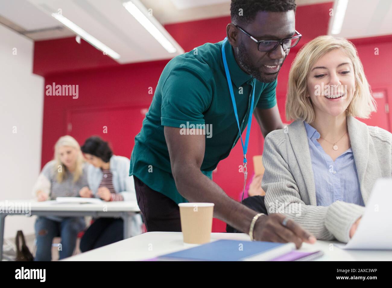 Teacher helping community college student at desk in classroom Stock Photo