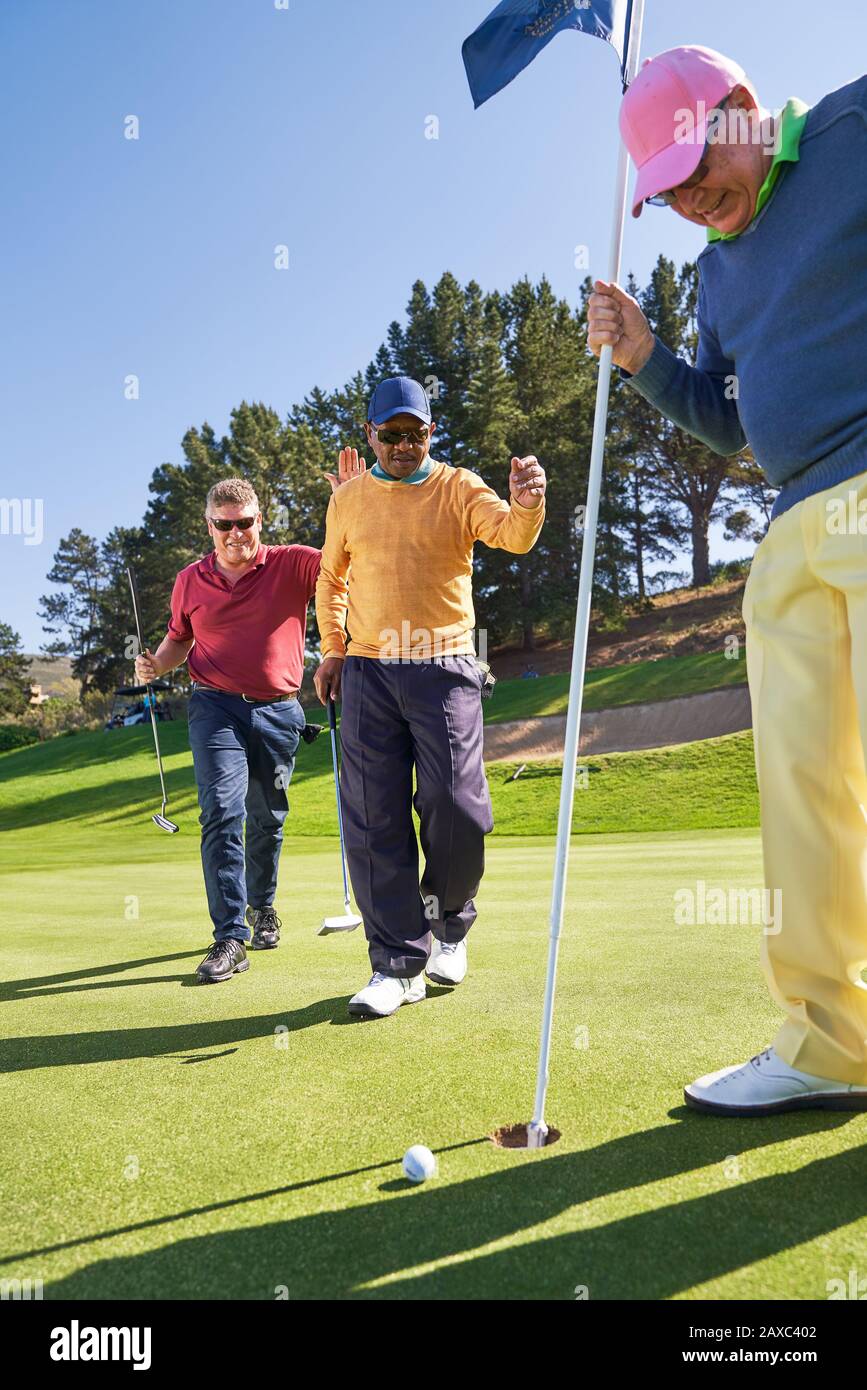 Male golfers at putting green hole Stock Photo